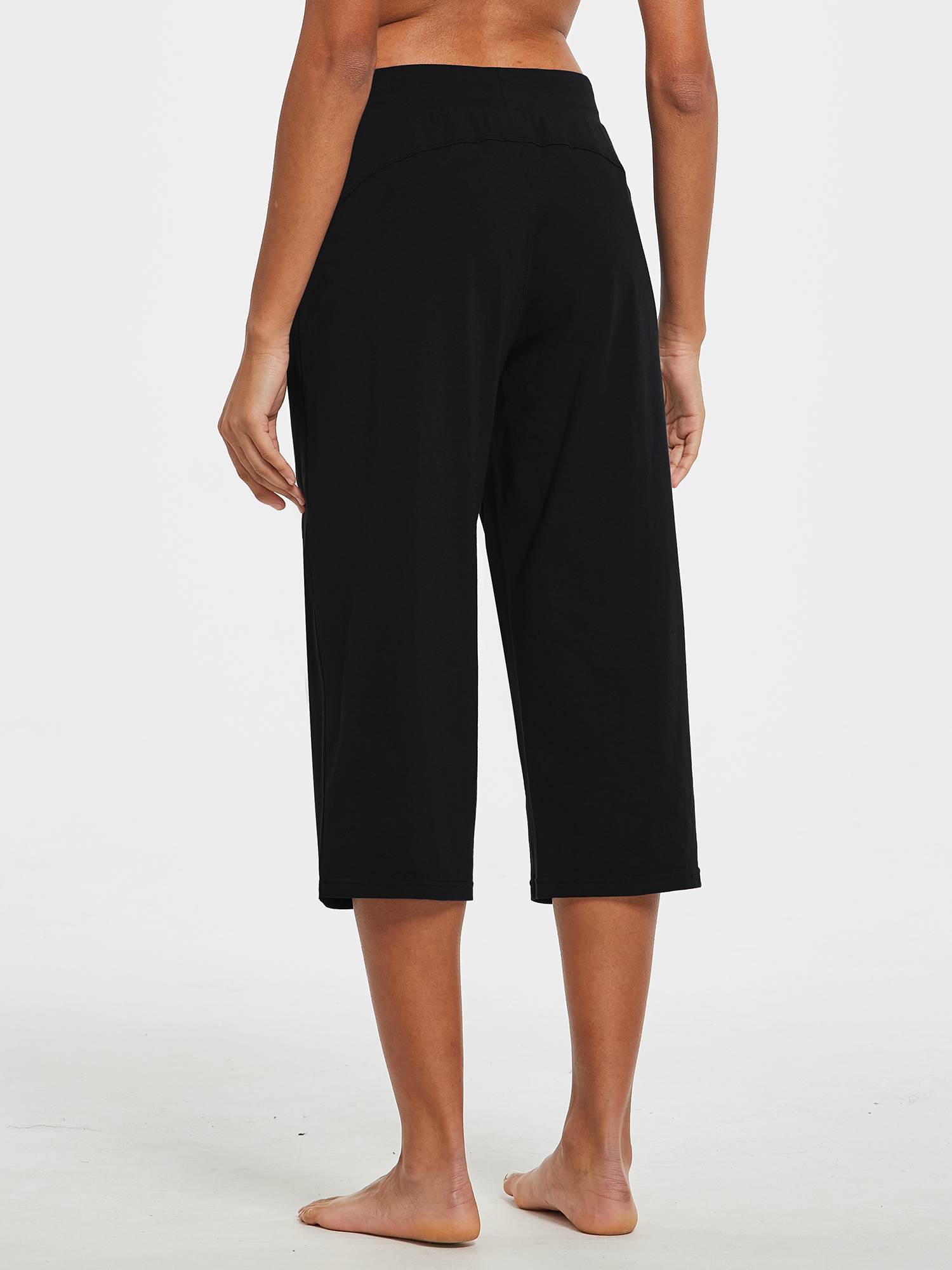 Woman from the back wearing black wide-leg cotton capri pants with a white background. #color_Black
