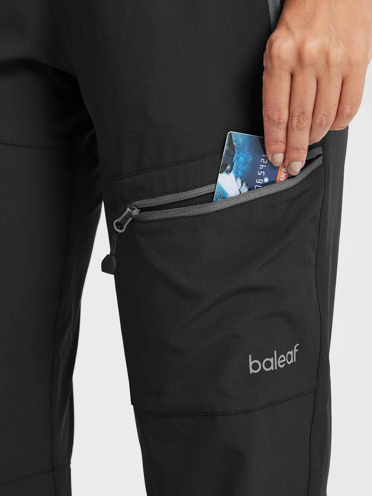 Black baleaf DWR hiking pants with zippered pocket for travel.