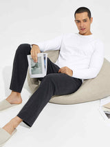 Man in charcoal cotton yoga cargo pants and white long-sleeve shirt relaxes on beanbag, reading. #color_Dark Gray