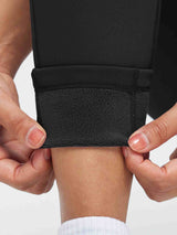 Hands reveal thick fleece lining inside black thickened thermal knit leggings.