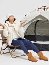 Woman in blue thermal leggings, cream puffer jacket, and beanie by tent. #color_Navy Blue