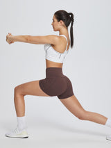 Brown 3" high-waisted compression biker shorts with tummy control, in stretching pose. #color_Dark Brown