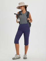 Woman in quick-dry navy blue 17" cycling hiking capris, zip pockets, sun hat. #color_Navy Blue