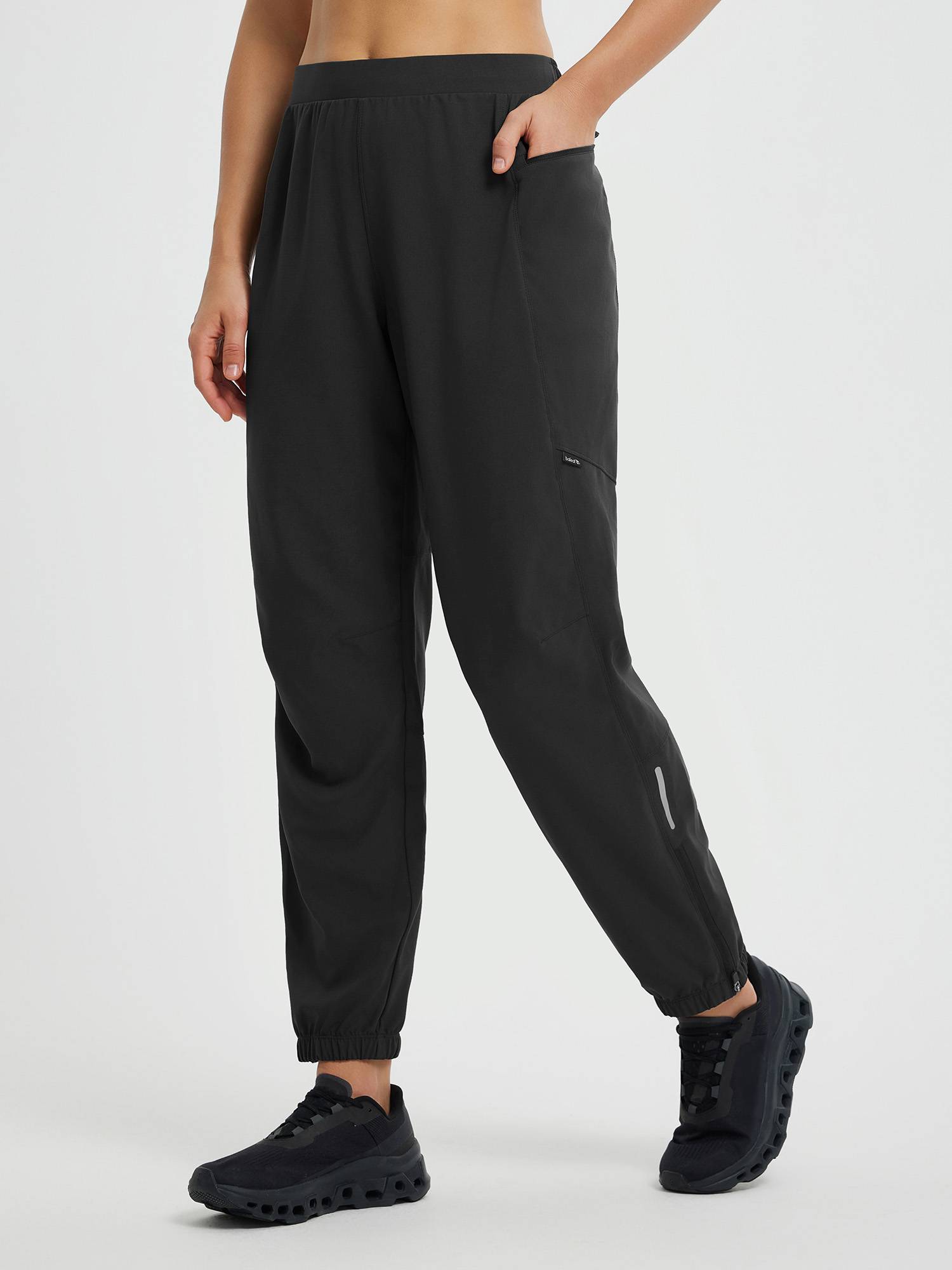 Black elastic tapered cycling pants with ankle zippers, reflective detail, and pockets. #color_Black