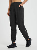 Black elastic tapered cycling pants with ankle zippers, reflective detail, and pockets. #color_Black
