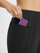 Black cycling pants detail: hand places card into zippered side pocket. #color_Black