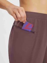 Detail of zippered pocket on brown tapered cycling pants, hand inserting card #color_Dark Brown