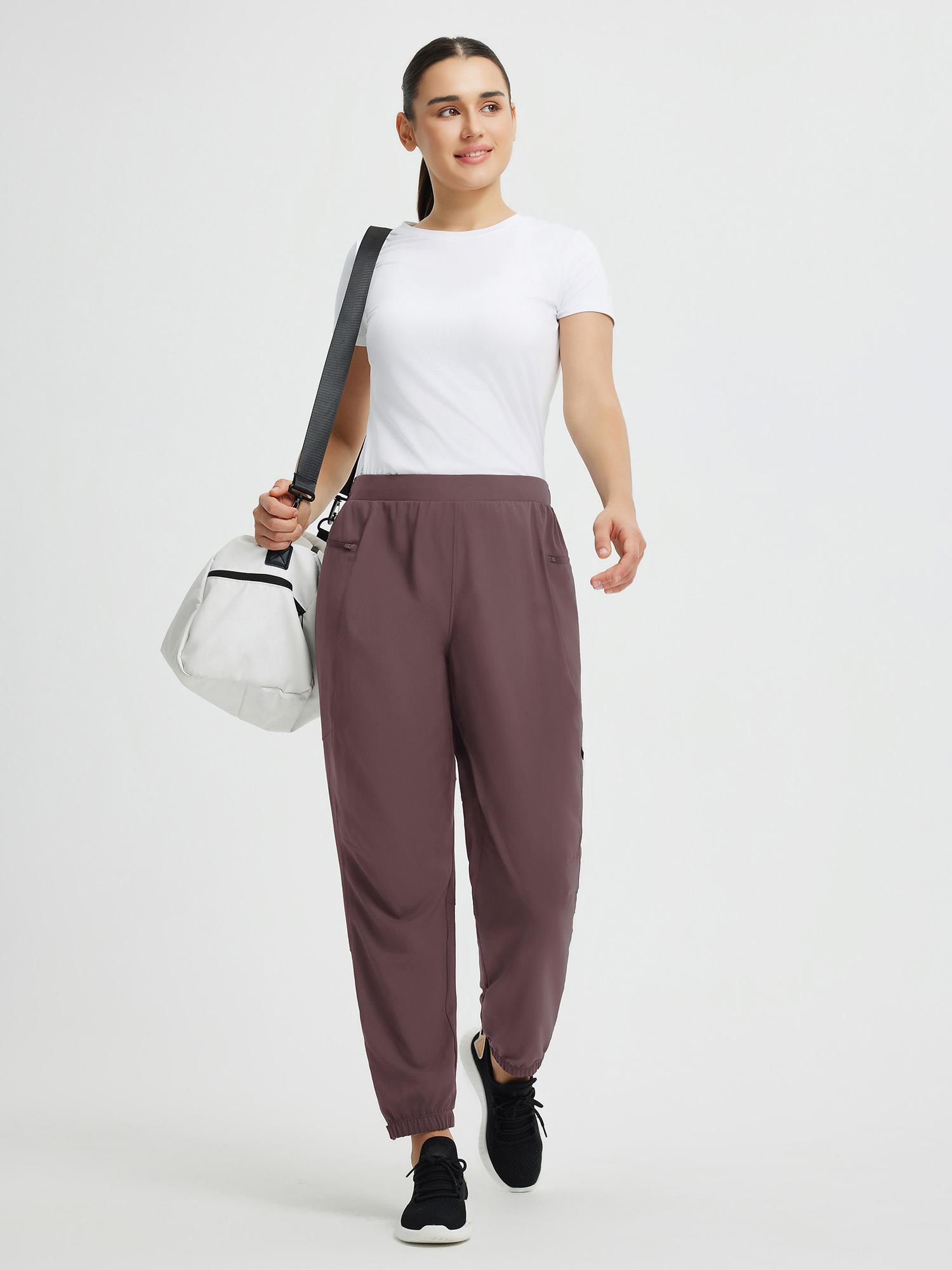 Brown elastic tapered cycling pants with side zippered pockets, worn by a woman. #color_Dark Brown