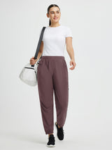 Brown elastic tapered cycling pants with side zippered pockets, worn by a woman. #color_Dark Brown