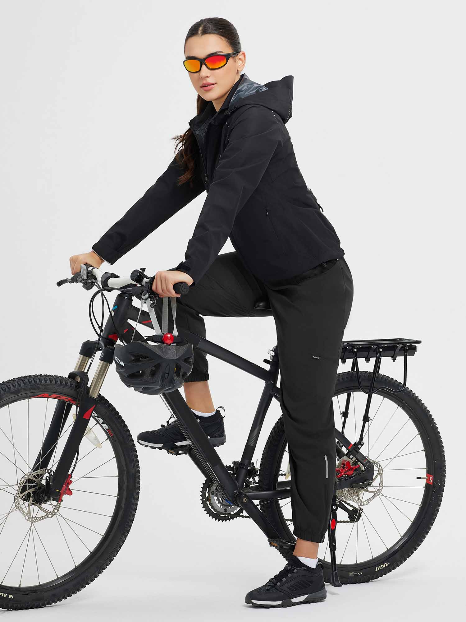 Woman in black elastic tapered cycling pants on bike with reflective details. #color_Black