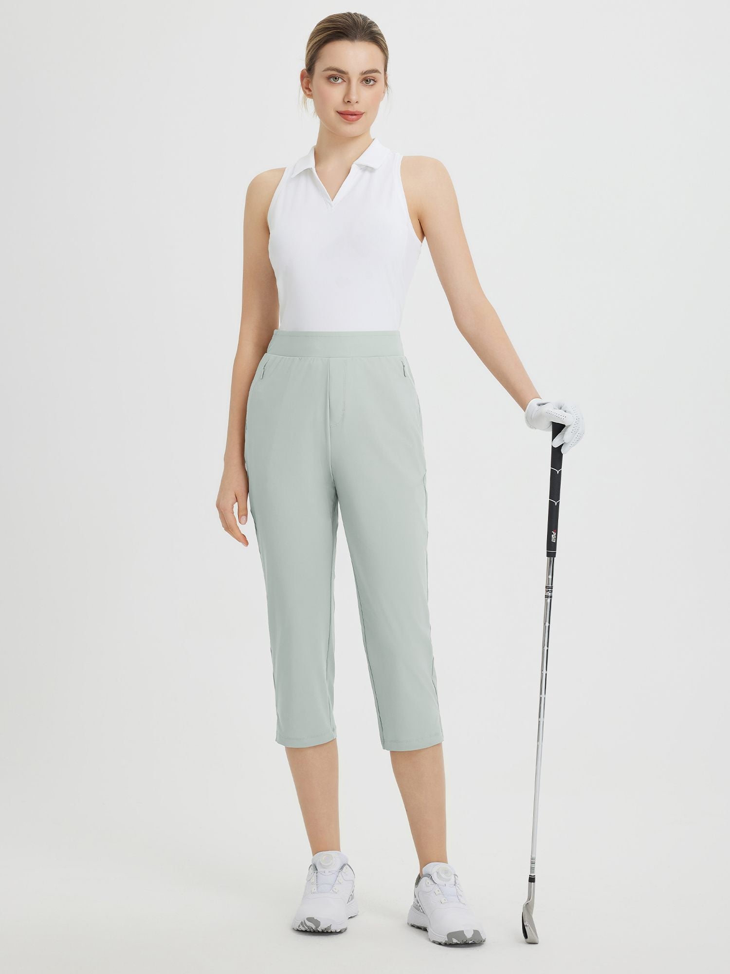 Woman wearing light green high-waisted cropped golf pants, 20-inch inseam, holding club. #color_Light Gray
