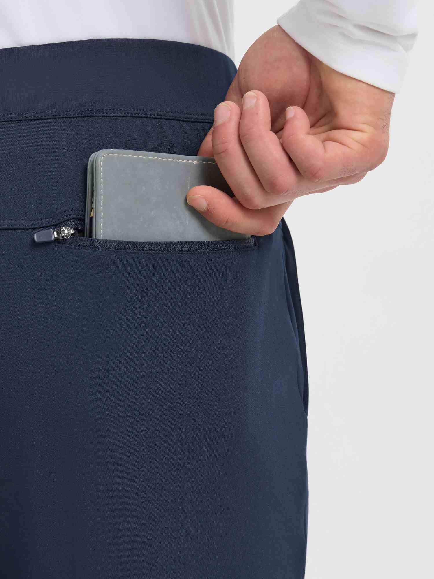Men's navy fleece golf pants with zippered utility pocket holding wallet. #color_Navy Blue