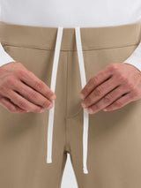 Men's tan golf pants with adjustable elastic waist and white drawstring #color_Brown