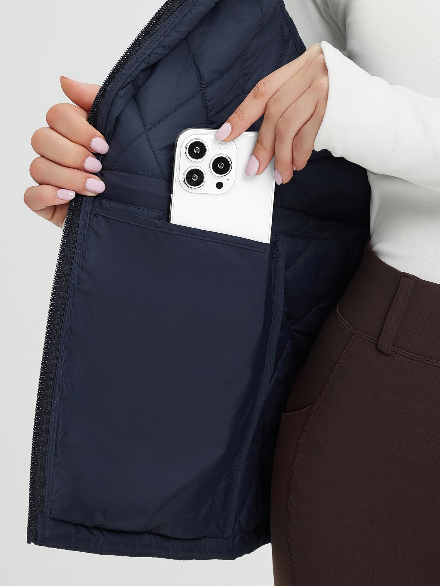 Navy blue quilted golf vest showing inner pocket storing a smartphone. #color_Navy Blue