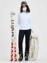 Woman in white ski fleece base layer with integrated protective face mask, holding skis. #color_White