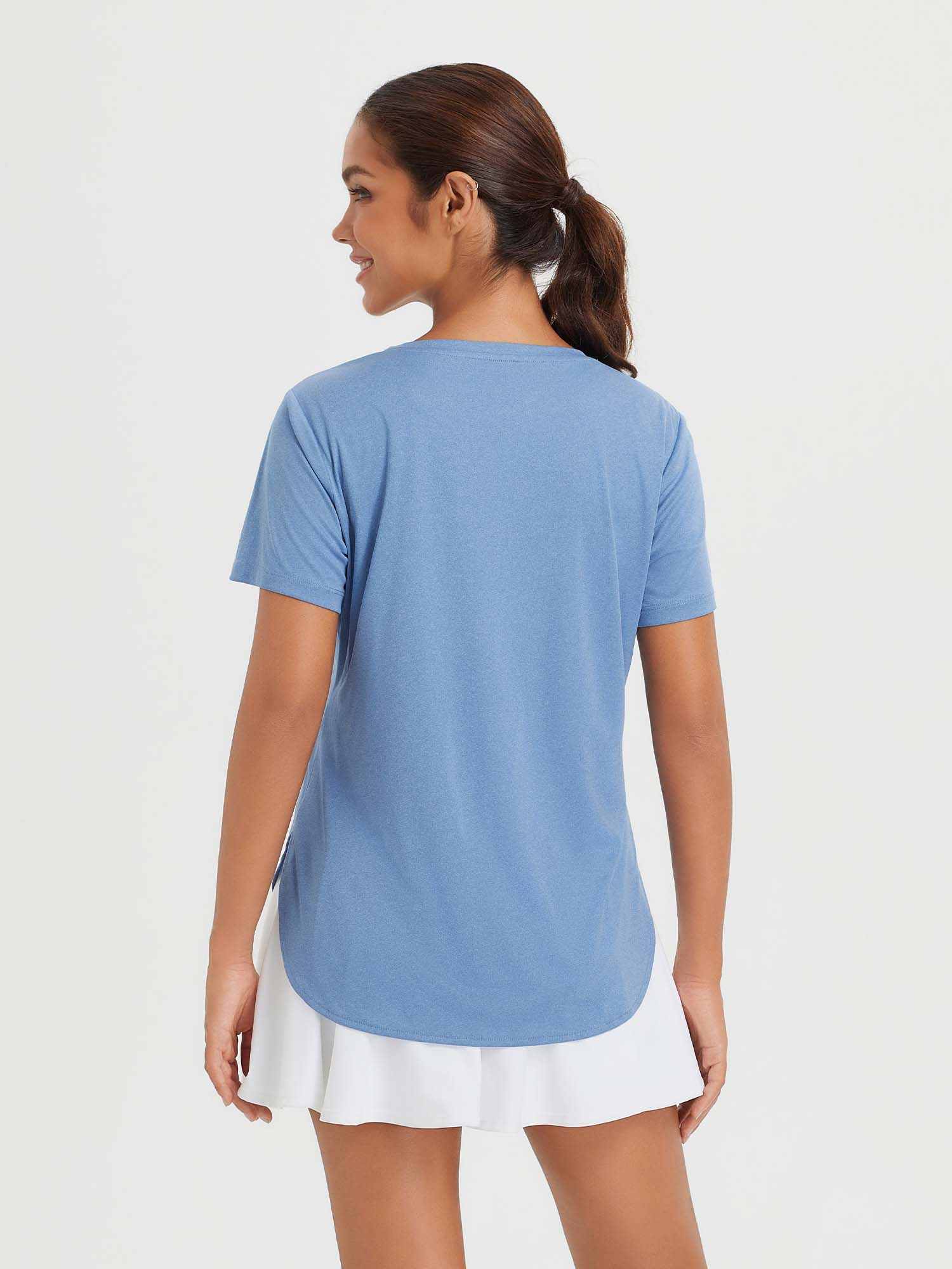 Woman wearing a blue short-sleeve crew neck t-shirt with a curved high-low hem and a white skirt. #color_Heather Light Blue