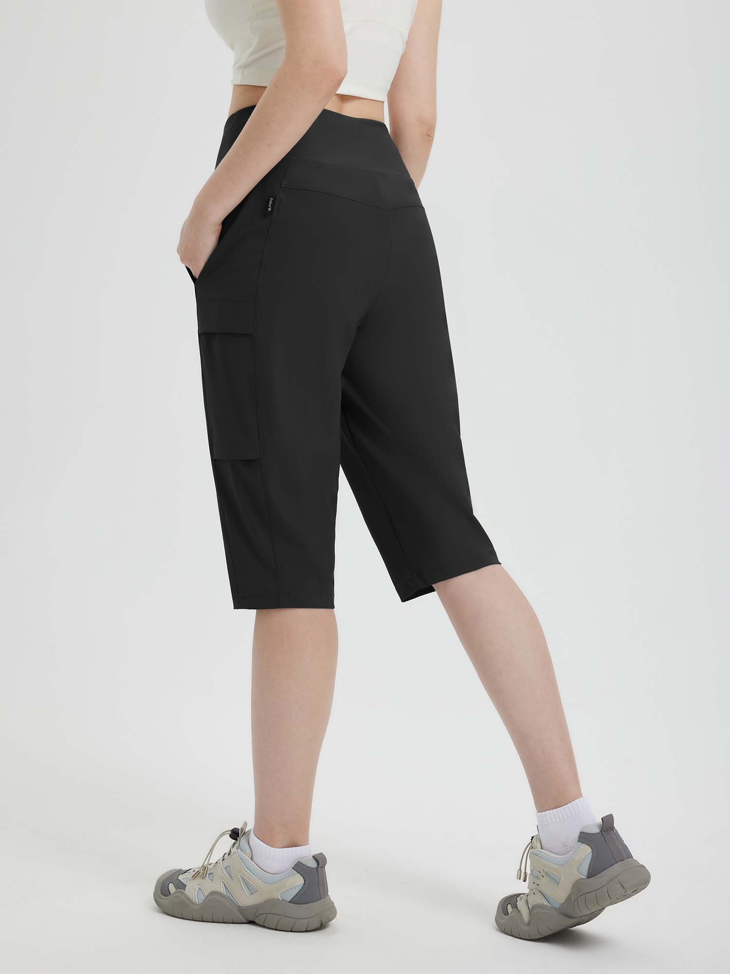 Woman wearing black 15" hiking shorts with multiple pockets and athletic shoes. #color_Black