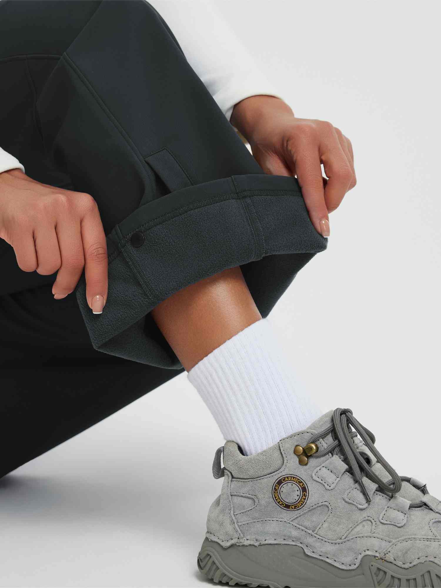 Women's dark outdoor softshell pants with thermal fleece lining and adjustable snap cuff. #color_Black