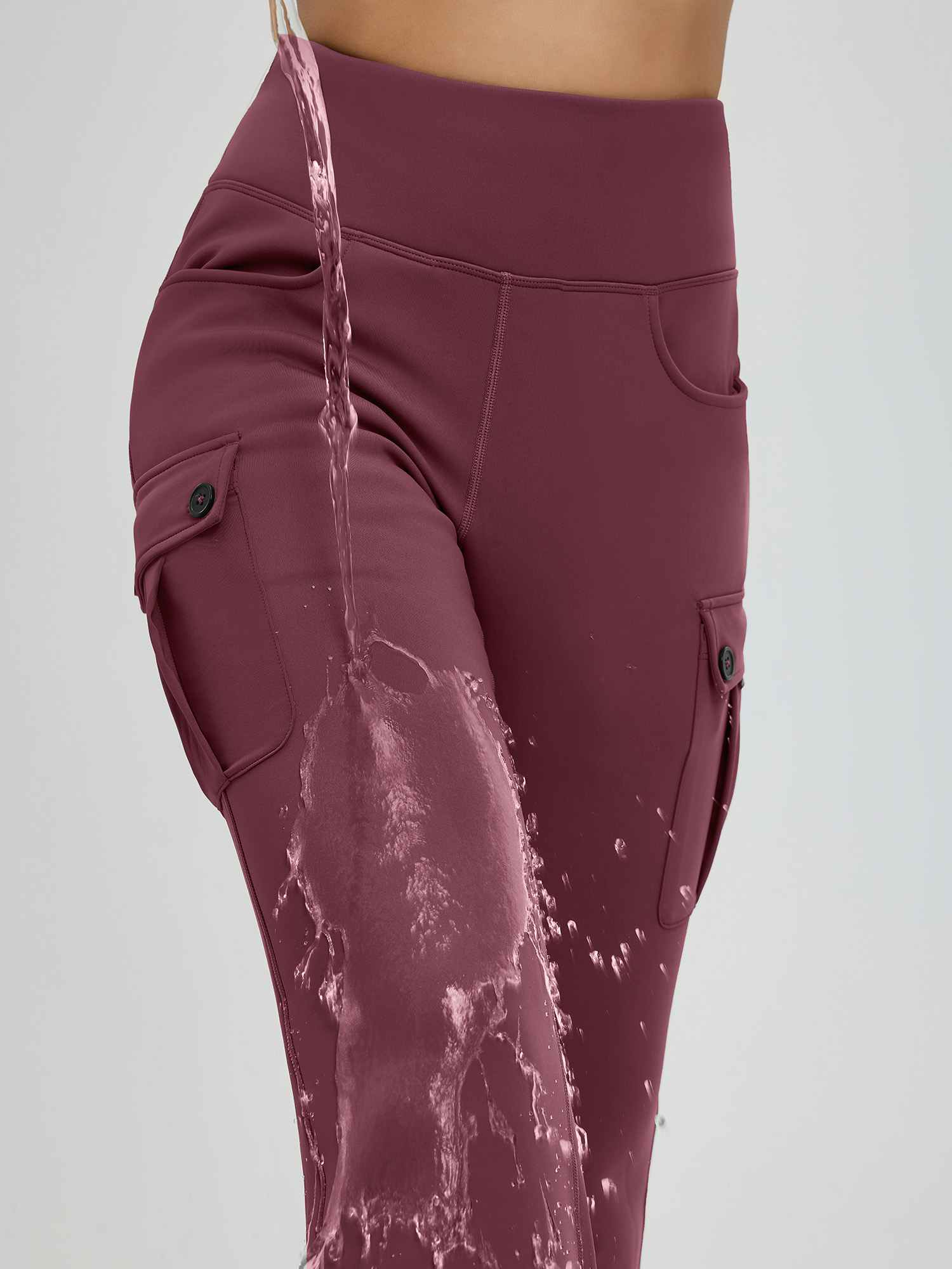 Water splashes on burgundy fleece-lined flared workwear pants with button cargo pockets. #color_Wine Red