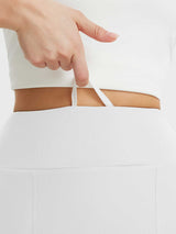 Women's white running skort waistband detail showing adjustable drawstring for custom fit. #color_White