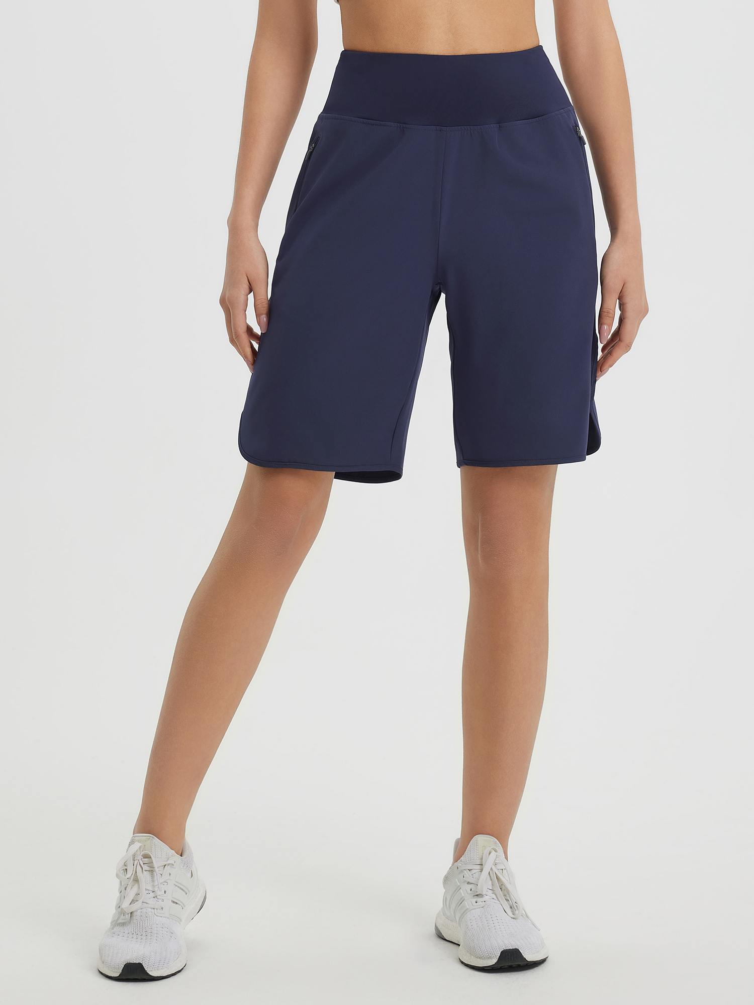 Women's navy blue 9" high-waisted running shorts with loose fit, curved hem, and zip pockets. #color_Navy Blue
