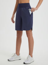 Women's navy 9" high-waisted running shorts with curved hem and side zip pocket holding smartphone. #color_Navy Blue