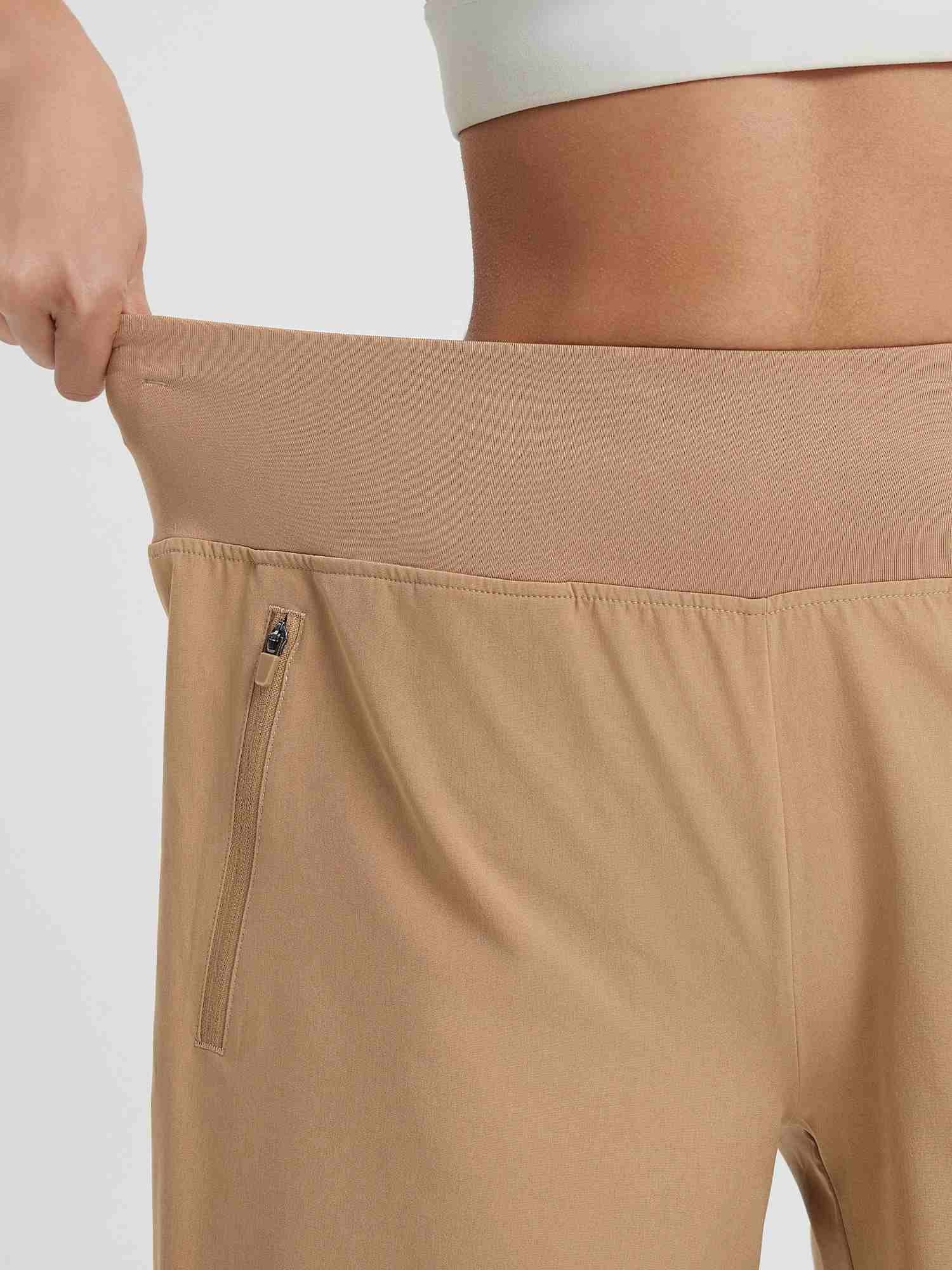 Beige women's 9" high-waisted running shorts with stretchy waistband and zippered pocket. #color_Brown