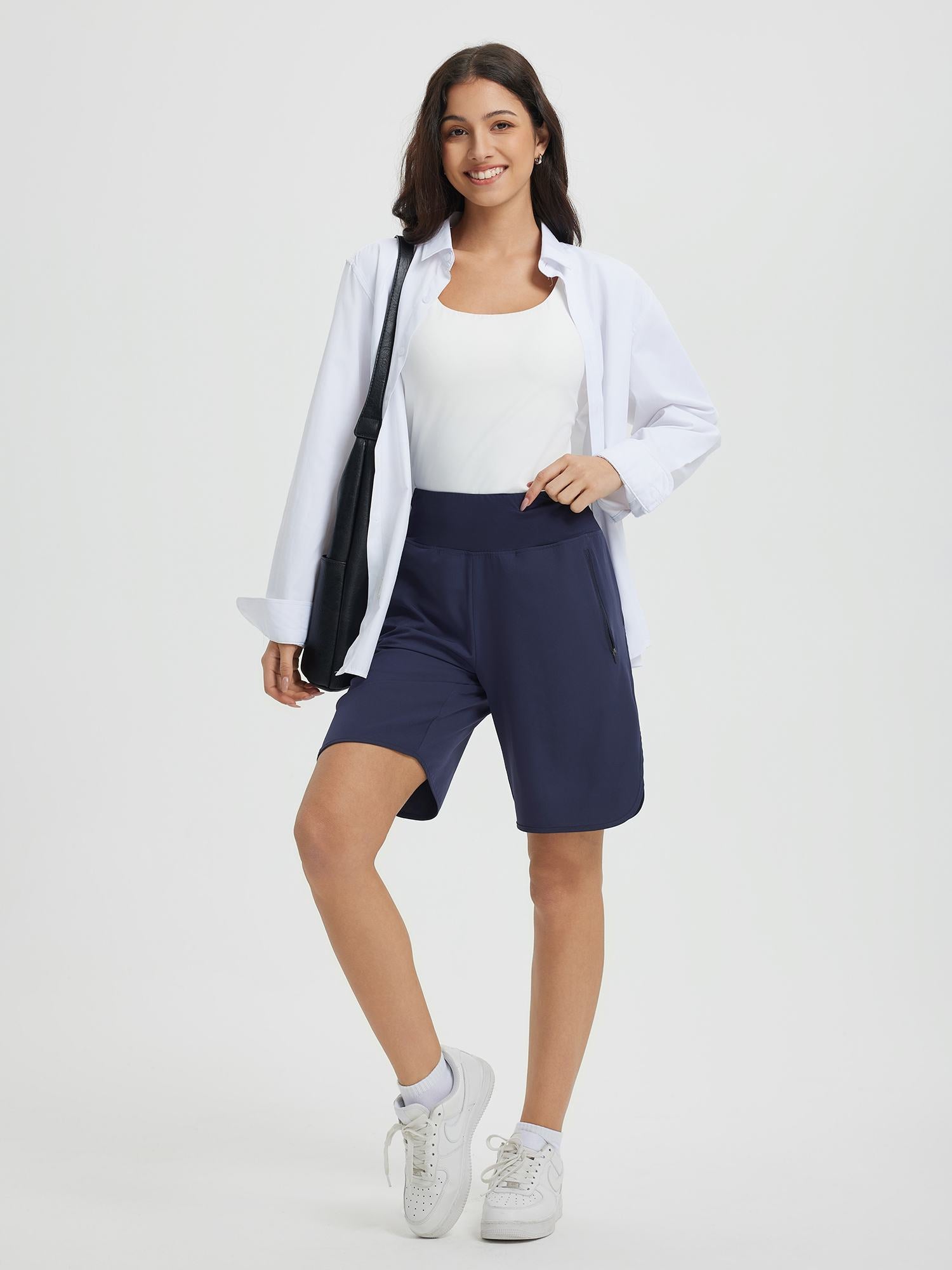 Navy blue Women's 9" high-waisted running shorts with secure side zipper pocket, on model. #color_Navy Blue