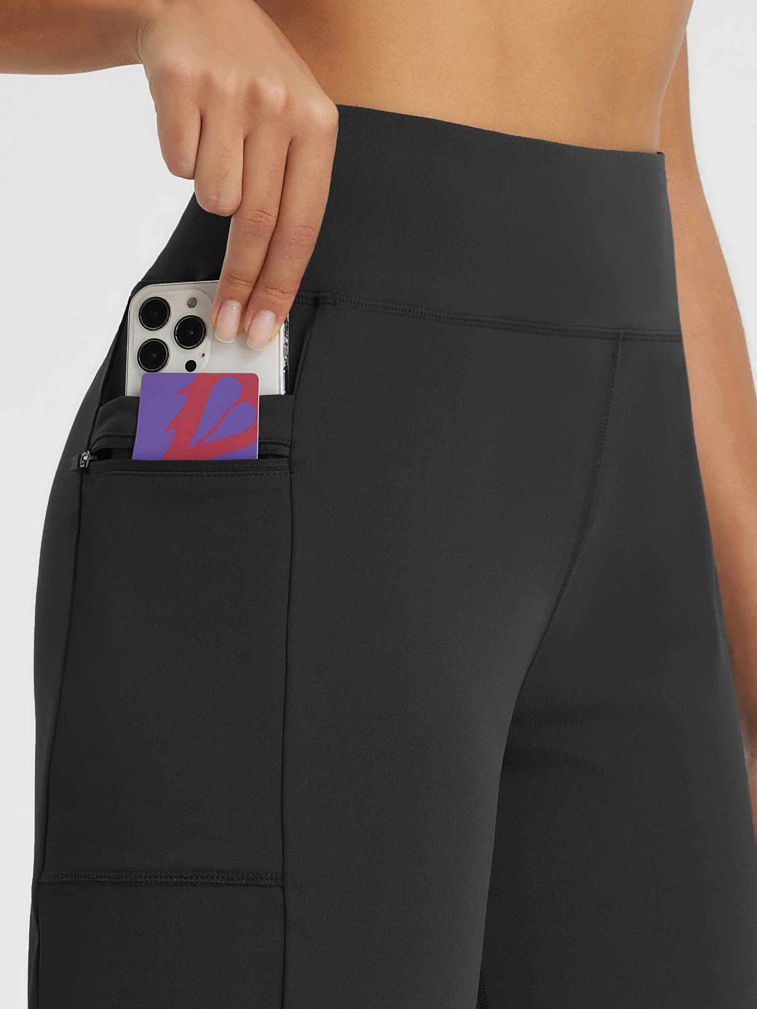 Black high-rise athletic shorts with zippered pocket holding phone. #color_Black