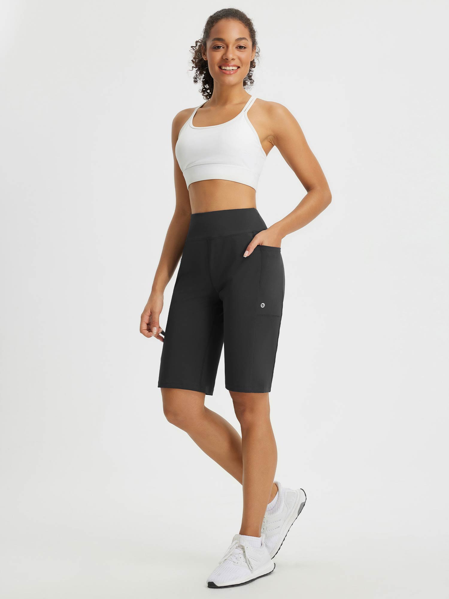 Move-Freely Set: Woman in black 12-inch high-rise shorts with pockets and sports bra. #color_Black