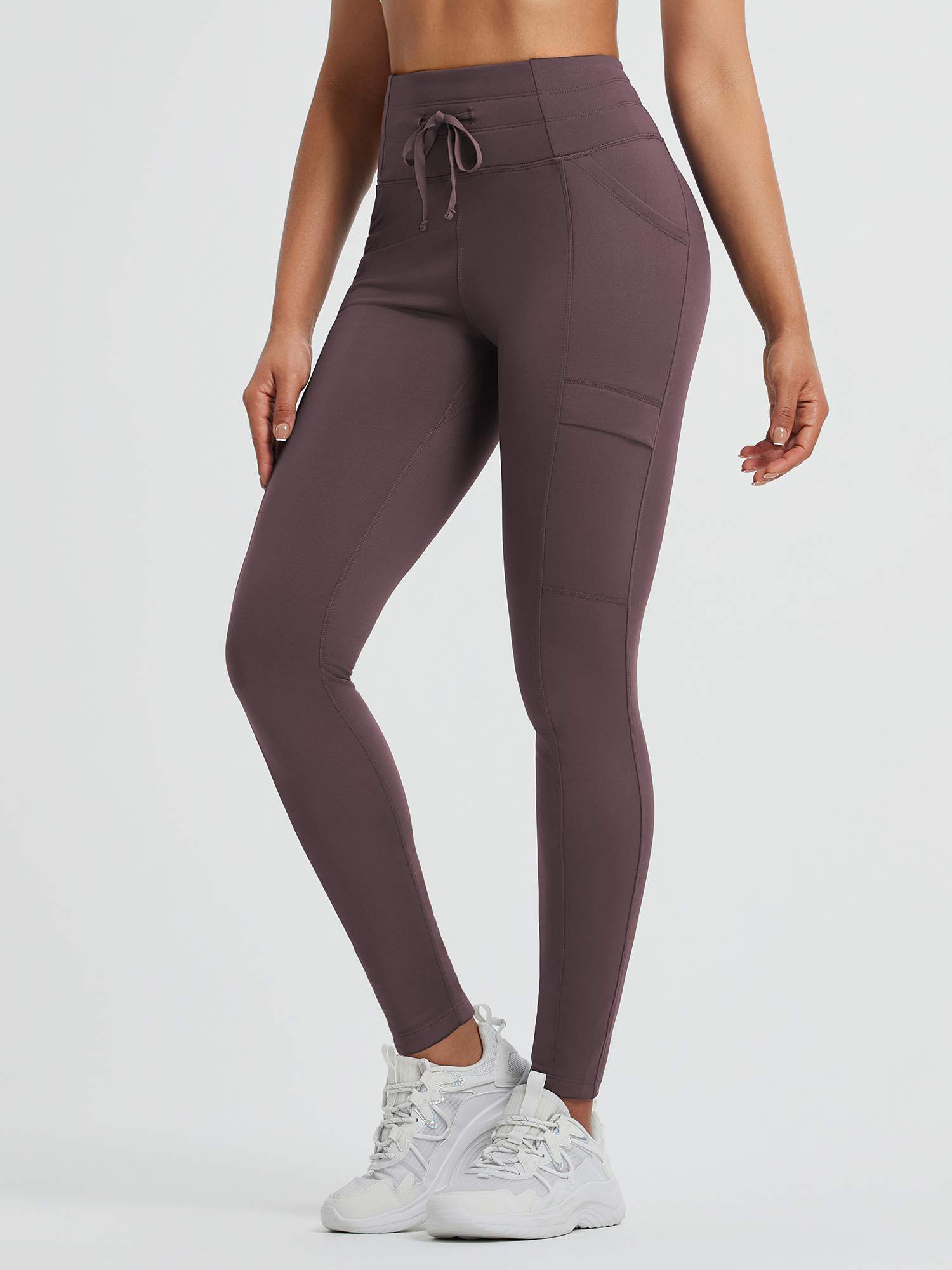 High-waisted running fleece leggings in plum with pockets and drawstring.