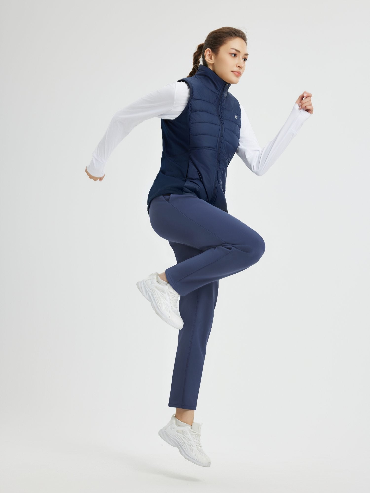 Women's heavyweight navy tapered thermal running pants, puffer vest, active pose. #color_Navy Blue