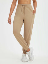 Women's beige running pants with fleece lining, patchwork pockets, and elastic cuffs.