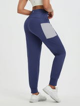 Women's navy fleece running pants with distinctive grey patchwork side pockets and cuffed hems. #color_Navy Blue