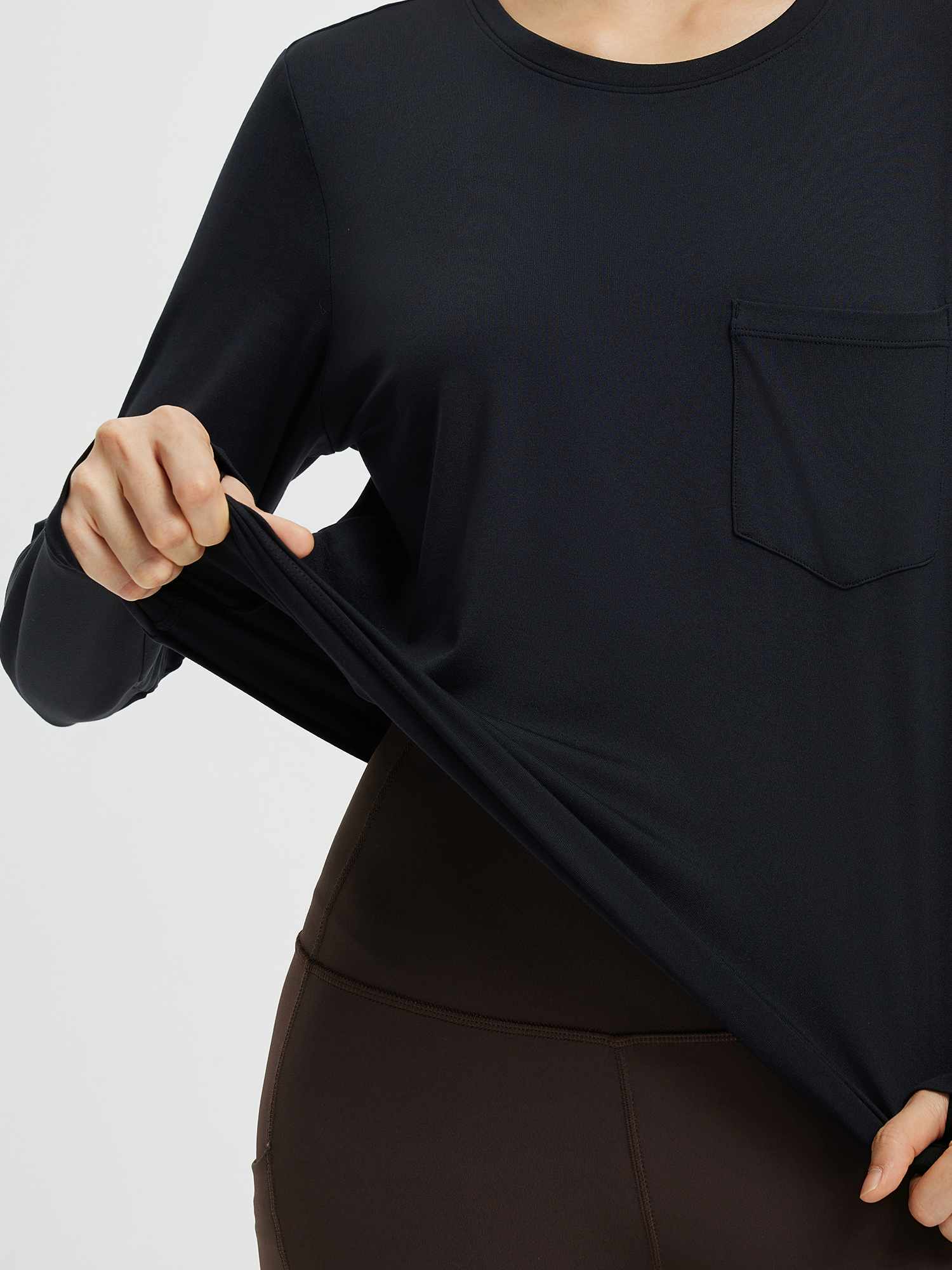 Black crewneck long-sleeve running top with chest pocket, demonstrating stretchy fabric. #color_Black