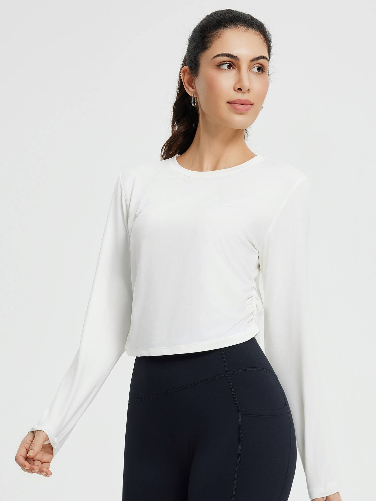 Women's crew-neck long-sleeve running shirt in white with ruched sides and thumb holes.