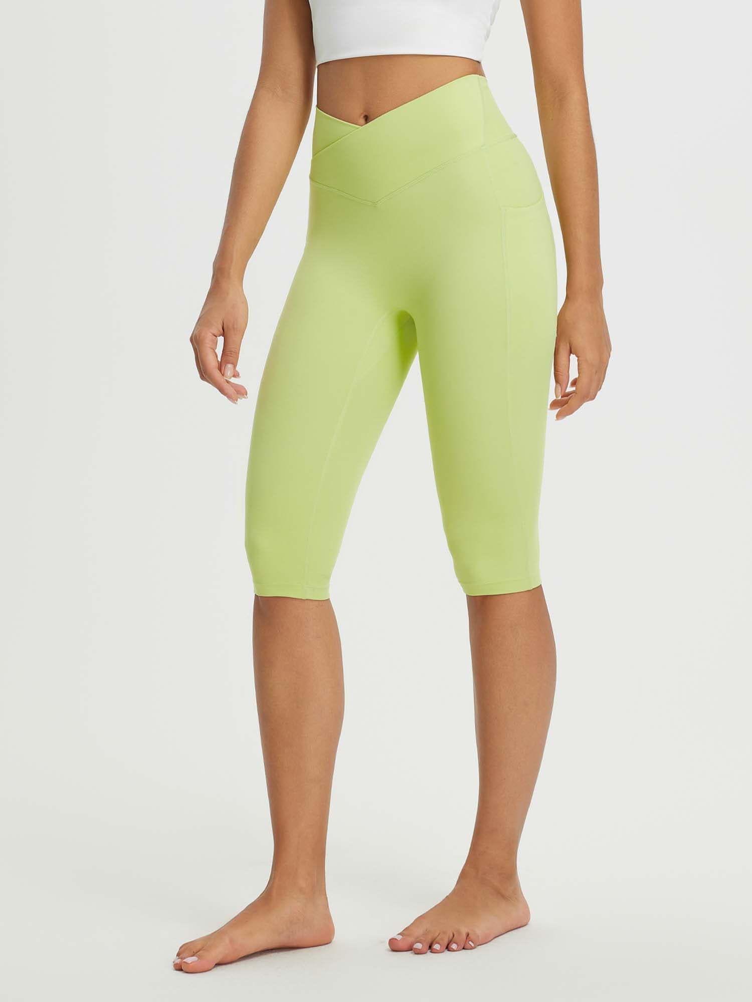 Women's 14" high-waisted crossover capris in light green with two side pockets and a V-shaped waistband. #color_Light Green