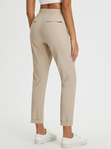 Beige high-rise tapered trousers with cuffed hem, ideal for outdoor travel.