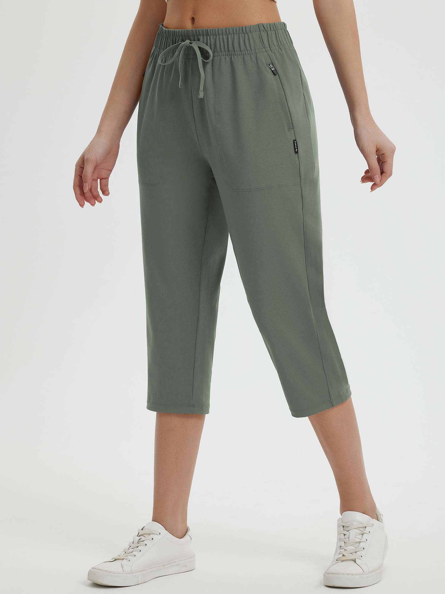Women's olive green 19" quick-dry yoga capri pants with drawstring and pockets, paired with white sneakers. #color_Army Green