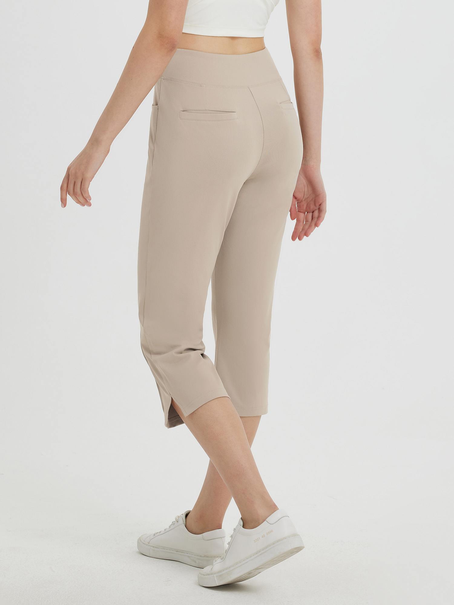 Women's high-waisted beige capri pants with 21-inch inseam and side slits, worn with white sneakers. #color_Khaki