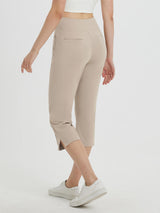 Women's high-waisted beige capri pants with 21-inch inseam and side slits, worn with white sneakers. #color_Khaki