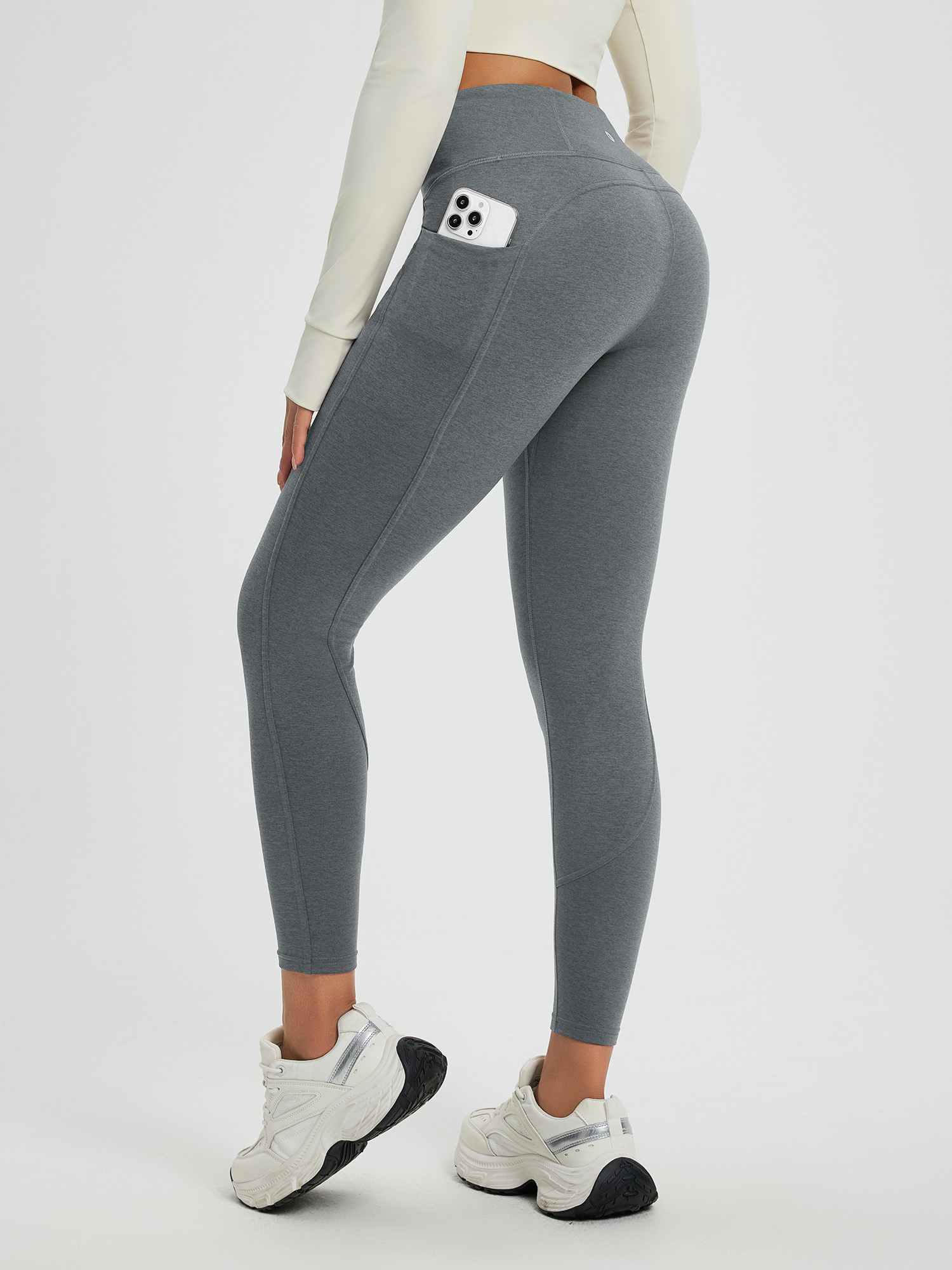 Grey women's high-waisted fleece-lined yoga leggings with side pocket holding phone. #color_Heather Dark Gray