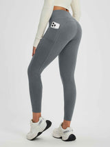 Grey women's high-waisted fleece-lined yoga leggings with side pocket holding phone. #color_Heather Dark Gray