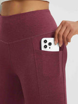 Burgundy heathered high-waisted yoga pants with V-seam detail and side pocket holding smartphone. #color_Wine Red