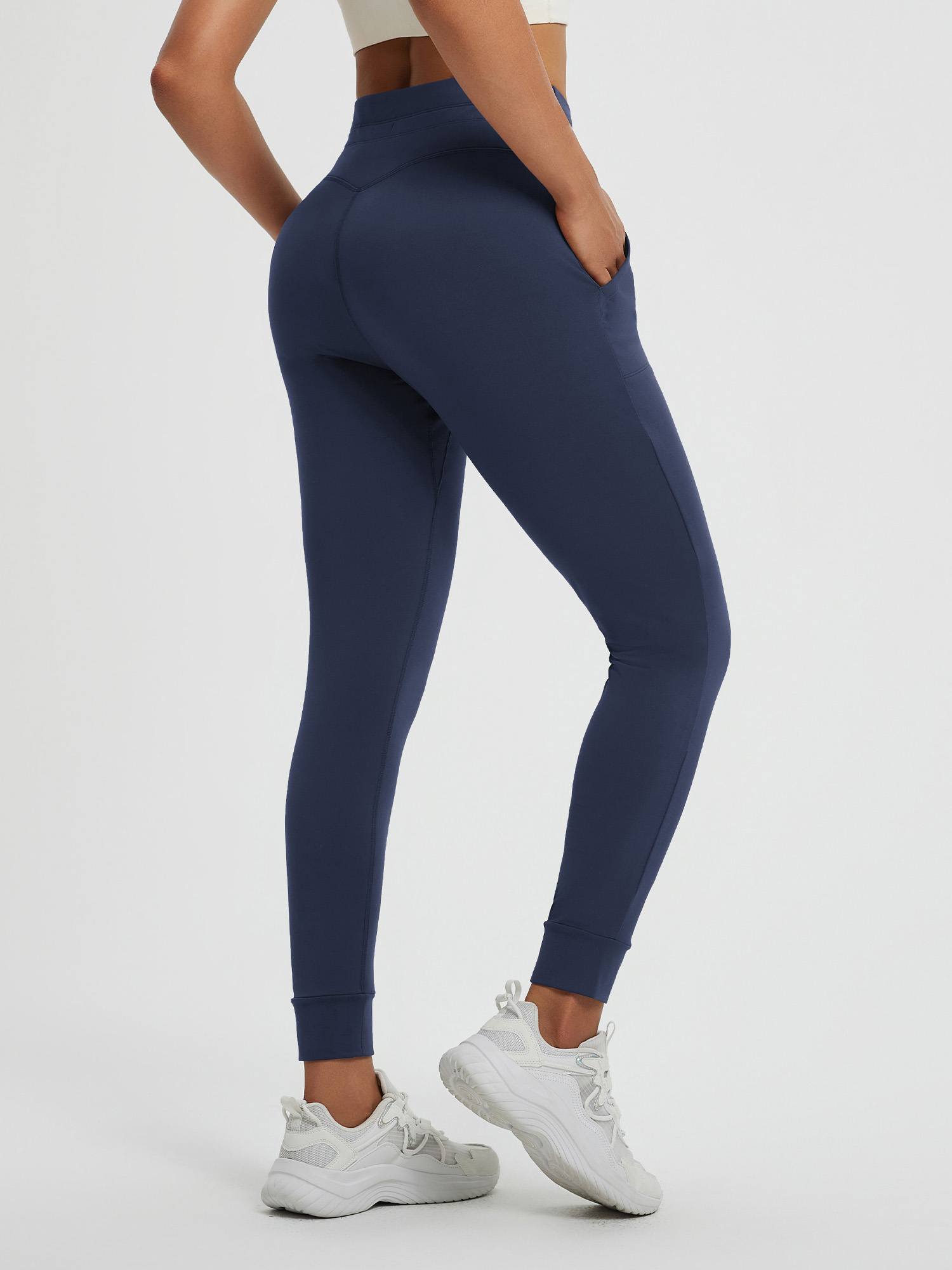 Women's navy blue high-waisted yoga leggings with tapered cuffed ankles and side pockets. #color_Navy Blue