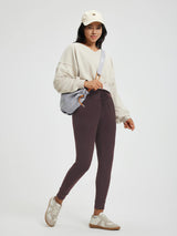 Model wears plum high-waisted fleece yoga leggings with pockets, cuffed ankles. #color_Dark Brown
