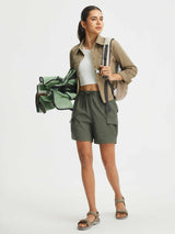 Baleaf UPF 50+ zip-off convertible hiking pants shown as olive green cargo shorts, on model with backpack. #color_Army Green