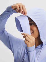 Woman smiles adjusting light purple Baleaf UPF 50+ sun jacket hood; shows thumbhole cuff. #color_Blue