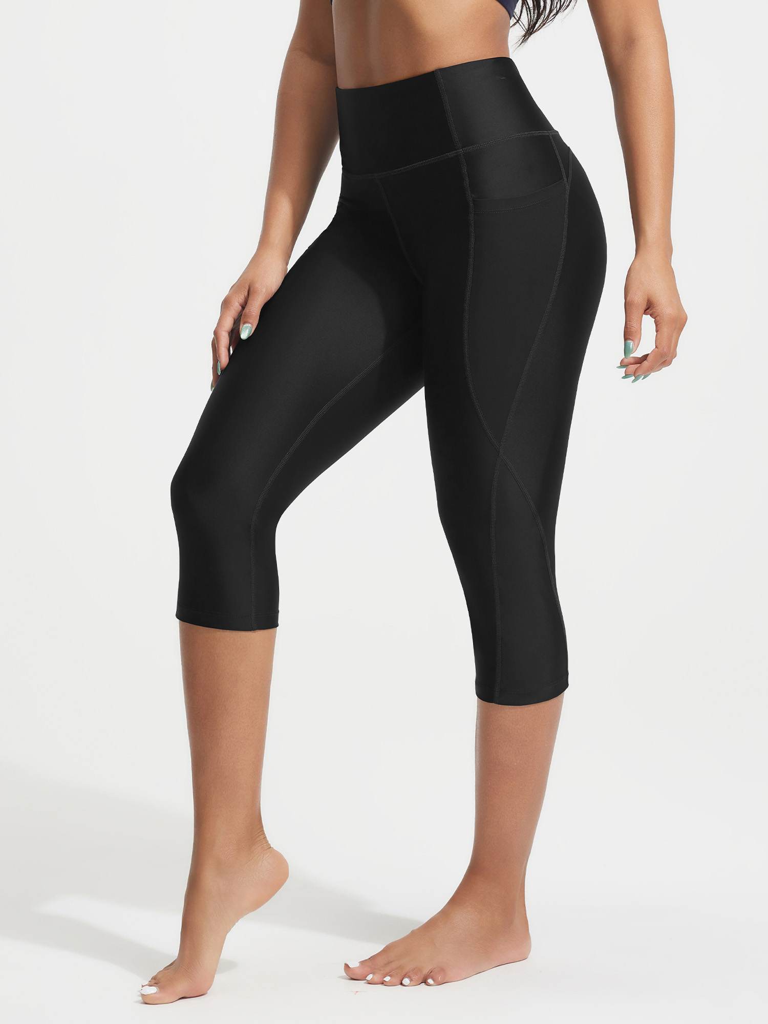 Model in black UPF50+ 18-inch high rise swim capris featuring side pockets and contour stitching. #color_Black
