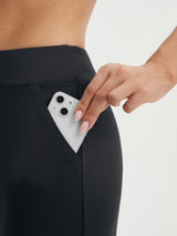 Baleaf black stretchy capri pants with deep side pocket holding a smartphone. #color_Black